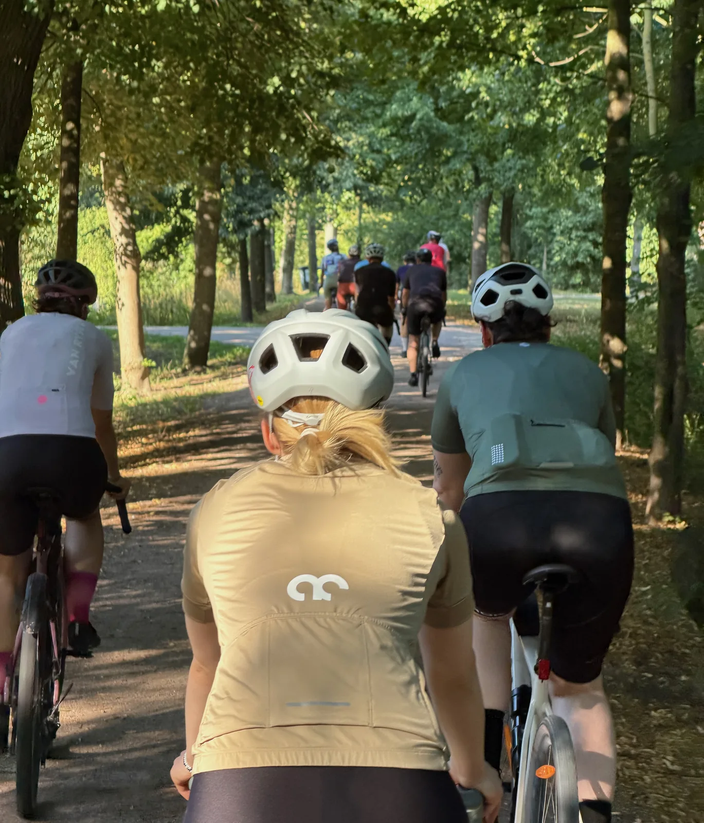 Mitglieder des social rides collective fahren gemeinsam durch eine grüne Allee